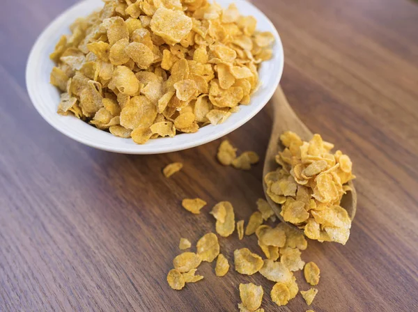 Corn flakes and bowl on wood table — Stock Photo, Image