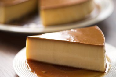  Beyaz tabak üzerinde ev yapımı karamel muhallebi puding ahşap masada kalmak