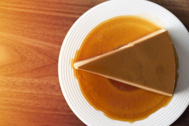 Beyaz tabak üzerinde ev yapımı karamel muhallebi puding üst görünümü ahşap masada kalmak