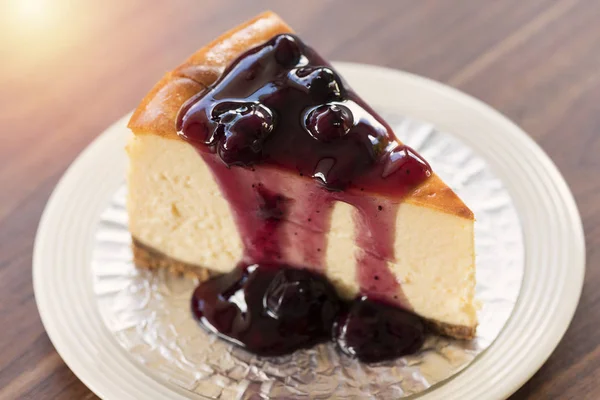 Beyaz tabak ve ahşap masa üzerinde ev yapımı yaban mersini New York cheesecake.