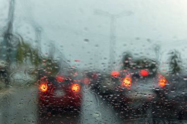 rüzgar kalkanı üzerinde yağmur damlası ile yolda durdurmak witn trafic ışık bir araba. Shot formu rüzgar kalkanı