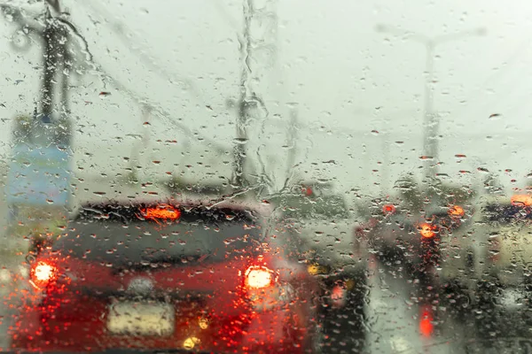 rüzgar kalkanı üzerinde yağmur damlası ile yolda durdurmak witn trafic ışık bir araba. Shot formu rüzgar kalkanı