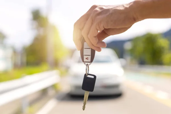 Arka planda arabanın anahtarlarını ve bulanık arabasını tutan adam..