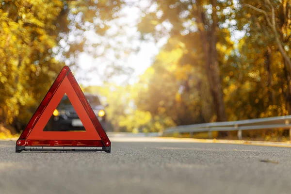 Red triangle, red emergency stop sign, red emergency symbol and black car stop and park on road.