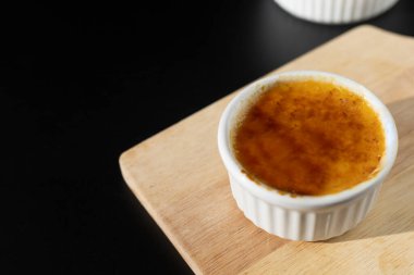 Ev yapımı creme brulee 'yi beyaz ramekin içinde, şekerli, siyah arka planda fotokopi alanı ile birlikte yakın. Fransız tatlı creme brulee