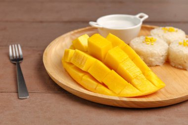 Taze sarı mango kabuğu ve dilimlenmiş pirinçli küp, tahta tabakta hindistan cevizi sütü. Tropik meyve. Tayland tatlısı. Tatlı meyve..