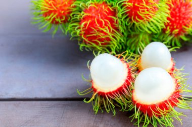 Ahşap masada taze Rambutan kabuğu soyulmuş ve bir sürü taze Rambutan arkaplanı var. Tropikal meyve soyulmuş taze rambutan.