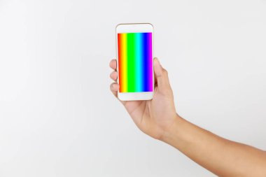 Ekranda cep telefonu tutan adam LGBT sembolleri gösteriyor. Gökkuşağı ekran ile el ele tutuşan akıllı telefon beyaz arka planda kopya alanı ile izole edildi. LGBT Kavram aktivizmi, toplum ve özgürlük. Lezbiyen, gey, biseksüel ve transseksüel.