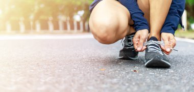 Ayakkabı bağcıklarını bağlayan koşucu kadını yakından çek. Pembe ayakkabısını bağlayan Asyalı kadınların elleri. Kadın yürüyüş parkında koşu ayakkabısı giyer. Sağlıklı ve zinde. Kopyalama alanı ile.