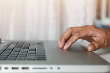 Erkek elleri evde çalışırken laptopta dokunmatik ped kullanır. Eller dokunma yastığına dokunur. Bulut veri ağı sosyal medya araması için internet kullan. Evden çalışmak yeni normal kavram.