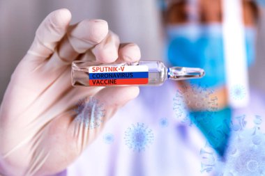 Covid-19 Coronavirus aşısı. Bilim adamının elleri kapalı. Covid-19 aşısının adı Sputnik-v. Virüs arkaplanlı cam şişe.