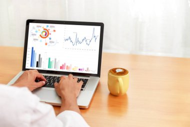 Bilgisayardaki istatistikleri analiz eden işadamı Hands bilgisayarını kullanarak online, iş ve finans grafikleri üzerinde çalışıyor.