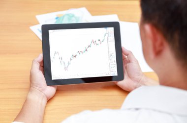 İş dünyası finans ve teknoloji kavramı. Dikiz üstü iş adamı elleri tablet ve şamdan sembolleriyle ekranda. İşadamı elleri tablet ağ denetim ticareti kullanıyor. Borsa alıp satıyor..