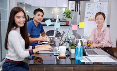 Dizüstü bilgisayar ve bilgisayar ile çalışan Asyalı küçük işletmeler çok ırklı girişimler. Özel İçişleri Bakanlığı 'ndan bir grup Asyalı ekip çalışması Coronavirus salgını arasında sosyal mesafeler