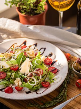 Tahta tabakta çeşitli peynir atıştırmalıkları ve beyaz tabakta salata.