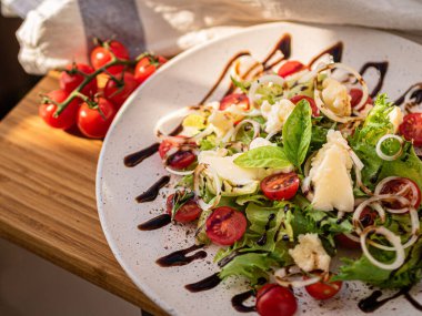 Tahta tabakta çeşitli peynir atıştırmalıkları ve beyaz tabakta salata.