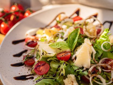 Tahta tabakta çeşitli peynir atıştırmalıkları ve beyaz tabakta salata.