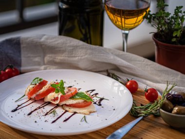 Tahta tabakta çeşitli peynir atıştırmalıkları ve beyaz tabakta salata.