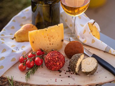 Tahta tabakta çeşitli peynir atıştırmalıkları ve beyaz tabakta salata.