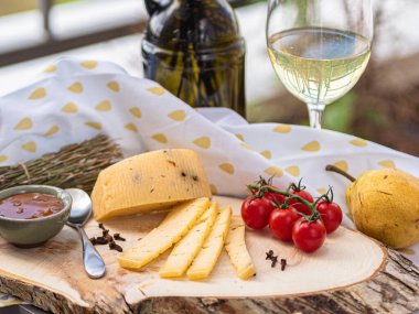 Tahta tabakta çeşitli peynir atıştırmalıkları ve beyaz tabakta salata.