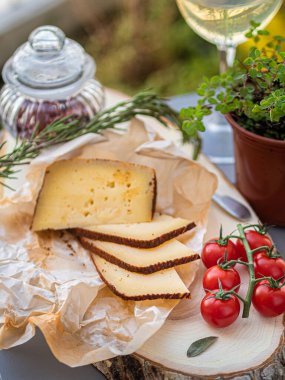 Tahta tabakta çeşitli peynir atıştırmalıkları ve beyaz tabakta salata.