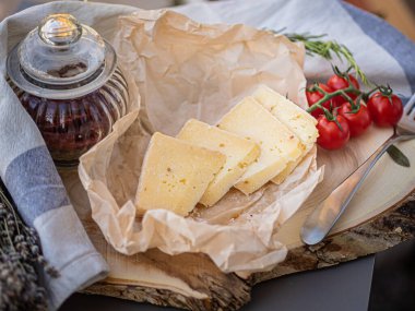 Tahta tabakta çeşitli peynir atıştırmalıkları ve beyaz tabakta salata.