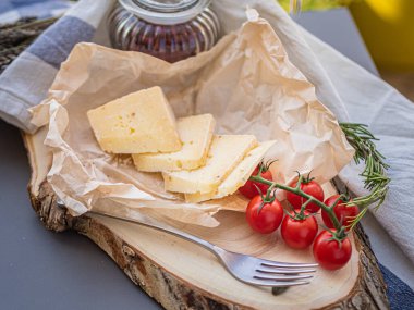 Tahta tabakta çeşitli peynir atıştırmalıkları ve beyaz tabakta salata.