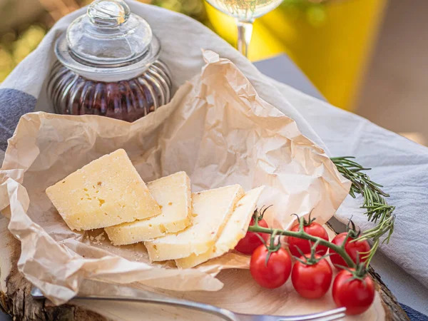 Tahta tabakta çeşitli peynir atıştırmalıkları ve beyaz tabakta salata.