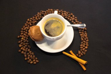 Kahve Americano beyaz fincan, kahve çekirdekleri, tarçın çubukları, Macaron
