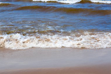 Deniz dalgaları kumlu kıyıyı yıkıyor.