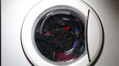 Çamaşır makinesi kapısı ve içinde dönen giysiler.