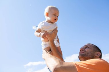 Mutlu baba küçük oğluyla sokakta, sahilde oynar. Aile, ebeveynlik ve insan kavramı