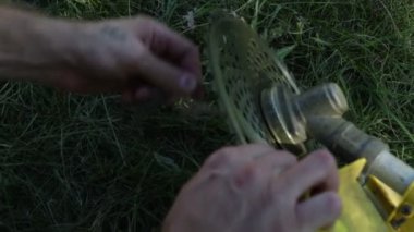 Bir adam çim düzelticiyi tamir eder. Elektrikli çim biçme makinesi