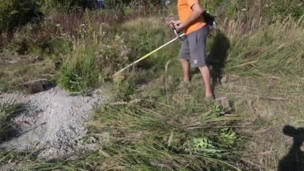Een Man Maait Het Gras Met Een Grasmaaier Trimmer Voor — Stockvideo