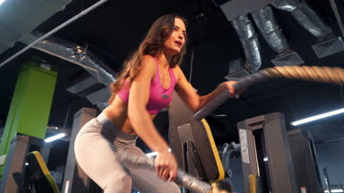 Savaşı ile kadın fitness salonunda egzersiz ipleri. Genç erkek spor giyim giymiş. Güzel vücut.