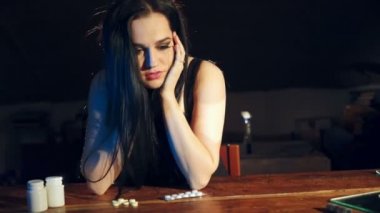 Evde karanlık odada bir sandalyede oturan depresif kadın. Yalnız kadın ilaçlar almaya gidiyor