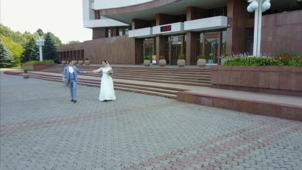 Charming Stylish Newlyweds Holding Hands While Walking Sunny Town Street — Stock Video