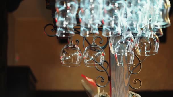 バーの上に逆さまにぶら下がっているきれいなワイングラス ラック レストランで バーテンダーは メガネを拭く — ストック動画