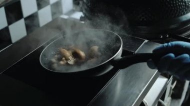 Şef bir tavada mantar yemek yapıyor. Pişirme Professional.