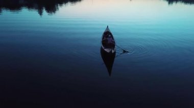 Geceleri bir gölde yüzen bir tekne içinde yatan genç bir kızın havadan görünümü. Gondolcu ile Gondol