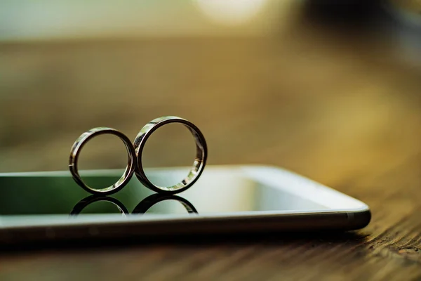 two gold rings are on the phone in the room. Rings in the form of eight are displayed on the background of screen glass