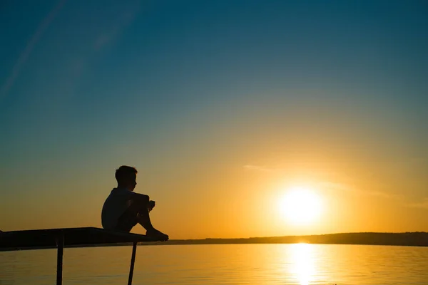 Niño Sienta Puente Mira Atardecer Junto Río Niño Está Impresionado — Foto de Stock