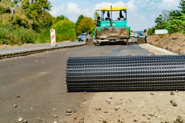 İnşaat ekipmanları yol çalışmaları için arka plan üzerinde yolun kenarında bir metal kafes bırakır