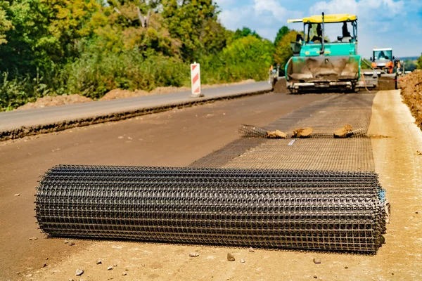 process of laying the road with using reinforced mesh technology and special machines. Close-up