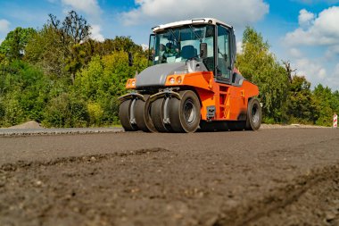 İnşaat Makinaları için yol çalışmaları yeni asfalt yaz mevsiminde ağaçlar arka plan üzerinde geçer