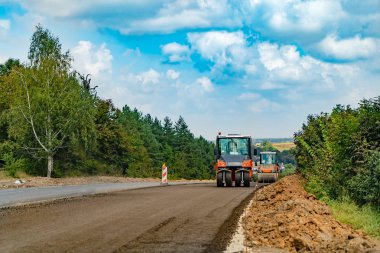 turuncu elbiseli bir adam çukurlar tamir yol yüzeyleri için özel makineler arka plan üzerinde bir üfleyici yardımıyla yol hazırlar