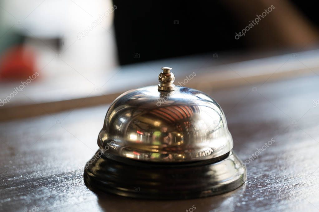 bell for call for a waiter of a gilded color stands on a wooden table in the restaurant. Close-up