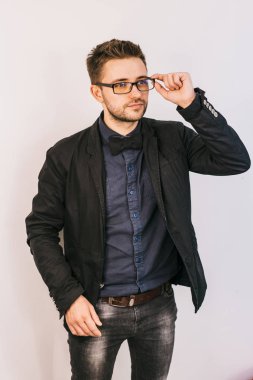yakışıklı adam siyah ceketli ve bununla birlikte güneş gözlüklü bir kenara stüdyoda beyaz bir arka plan üzerinde görünüyor.