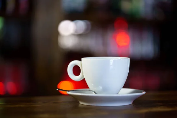 一张带有茶托和勺子的白色杯子在餐厅的木桌上 — 图库照片