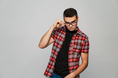 yakışıklı adam ekose gömlekli teşkil etmektedir ve dokunur gri bir arka plan üzerinde siyah bir RIM ile gözlük için eliyle